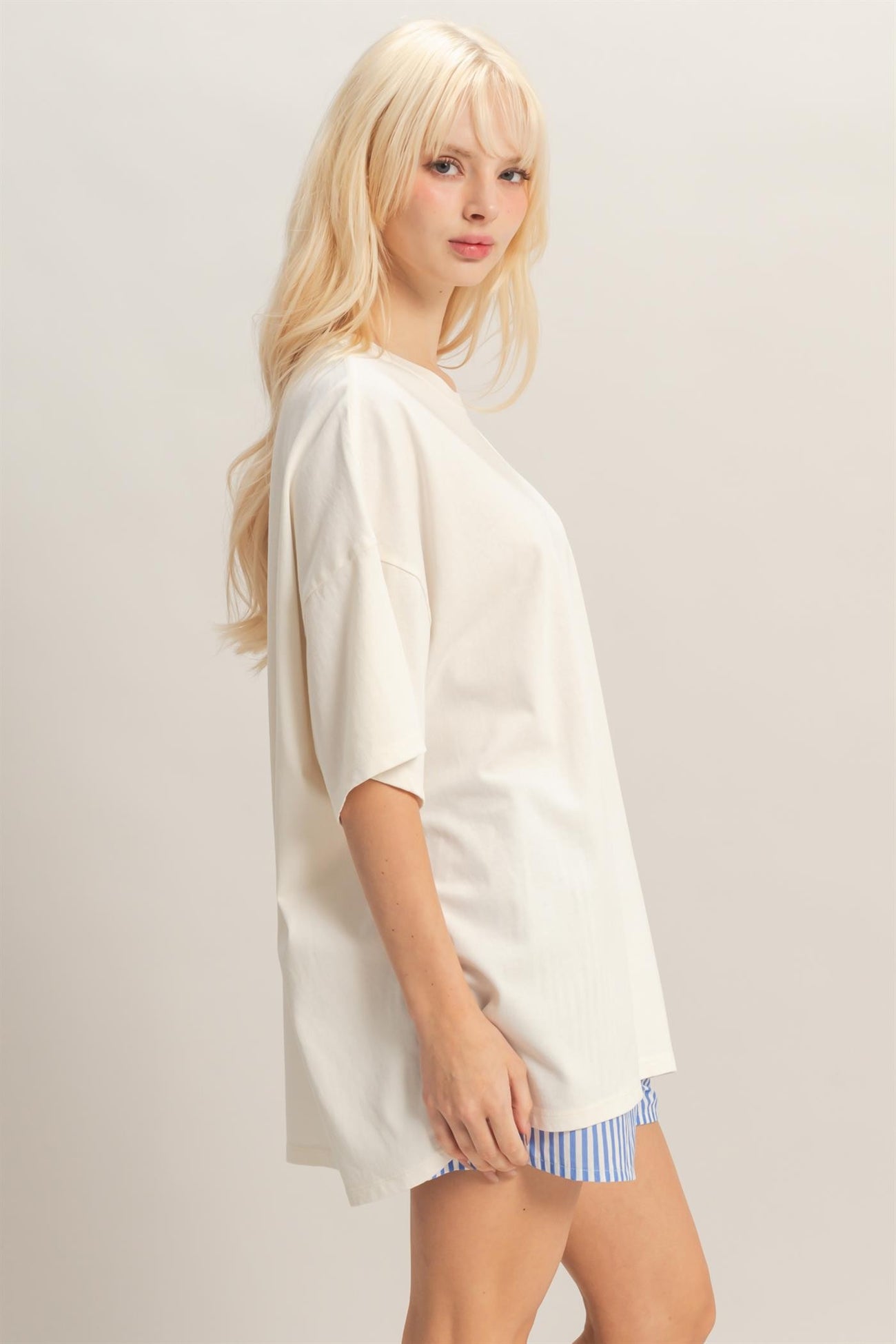 woman wearing an oversized cream short sleeve top paired with blue and white striped shorts