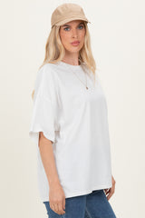 woman wearing a white oversized t-shirt and a beige cap paired with blue jeans