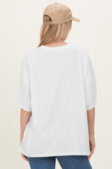 woman wearing a white oversized t-shirt and a beige baseball cap, viewed from the back