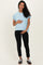 woman wearing a light blue maternity top and black maternity pants, holding her baby bump
