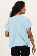 woman wearing a light blue oversized maternity t-shirt with rolled sleeves, showing a relaxed fit and back view