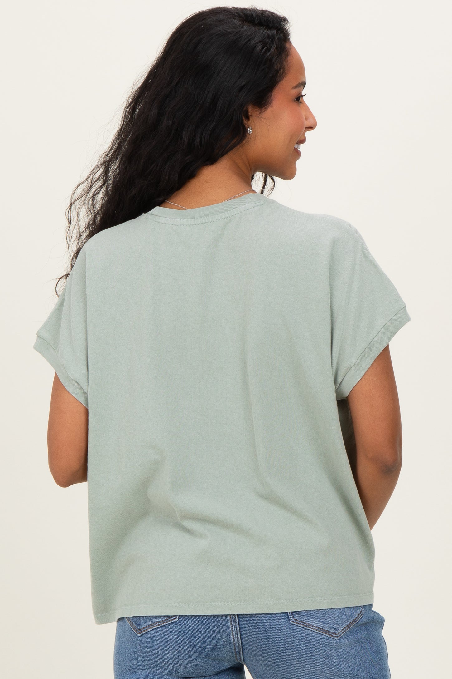 woman wearing a light green maternity top with rolled sleeves and a relaxed fit, viewed from the back