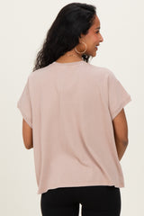 woman wearing a light taupe oversized maternity top, viewed from the back, with short sleeves and a relaxed fit