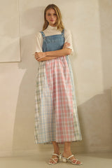 woman wearing a denim and plaid midi dress with a fitted top and flared skirt, paired with white sandals