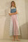 woman wearing a denim and plaid midi dress with a fitted top and flared skirt, paired with white sandals