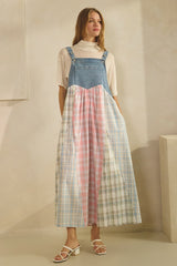 woman wearing a denim and pastel plaid color block maxi dress with a white turtleneck underneath and strappy sandals
