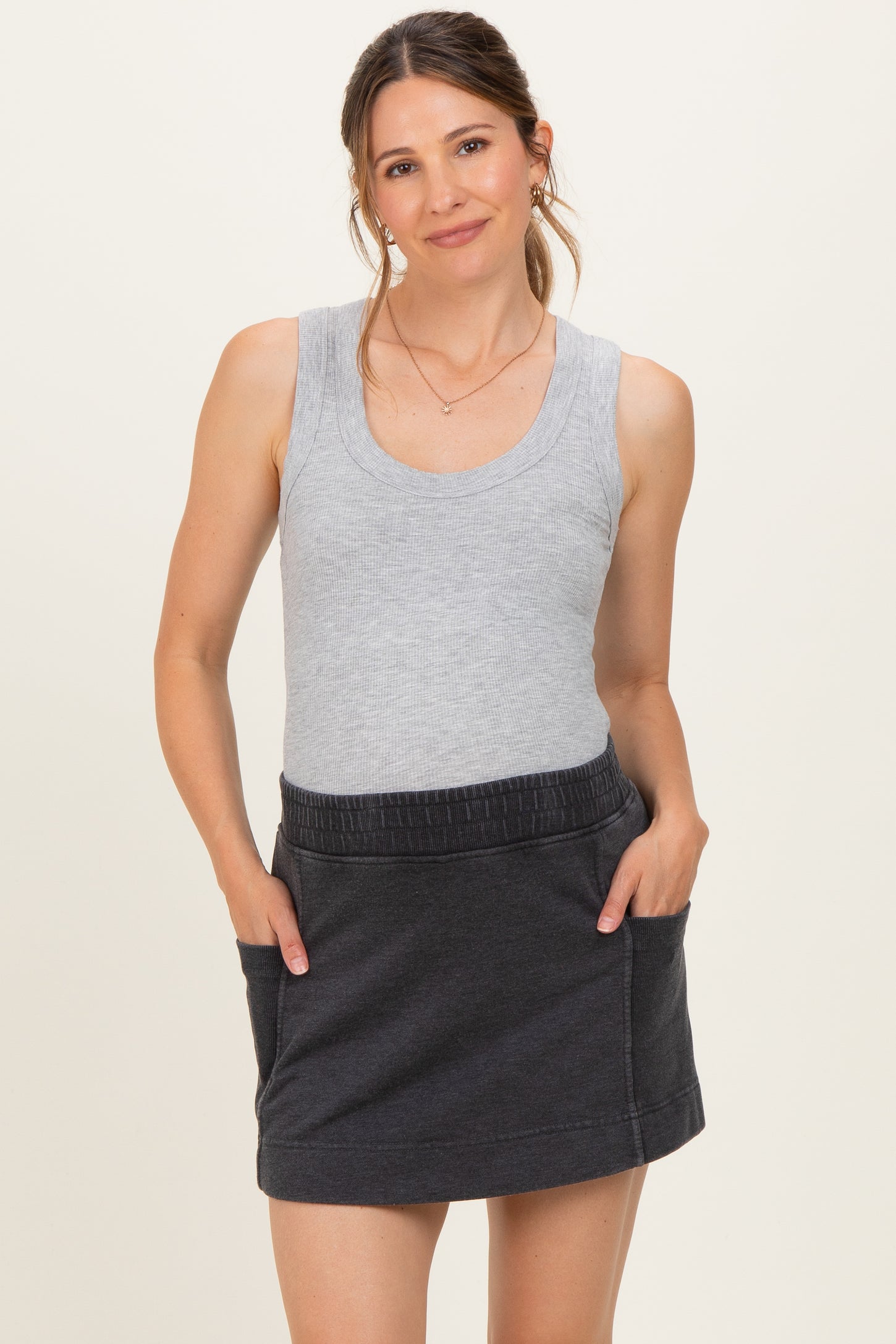 woman wearing a gray maternity tank top and a dark gray maternity skirt with pockets