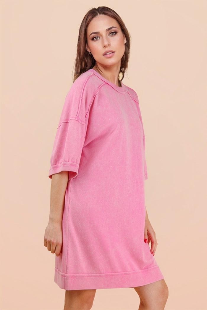 woman wearing a pink oversized t-shirt dress with short sleeves and a relaxed fit