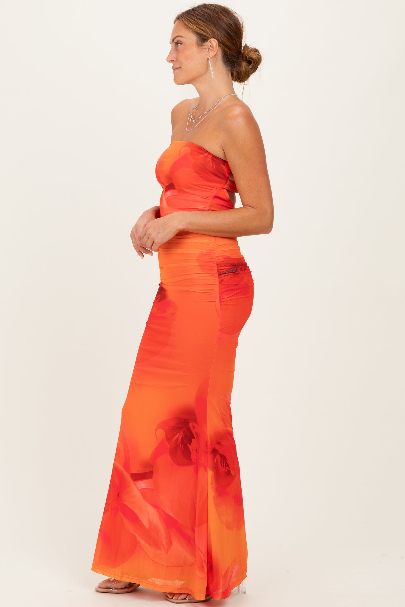 woman wearing a strapless red floral maxi dress with a form-fitting silhouette and side ruching