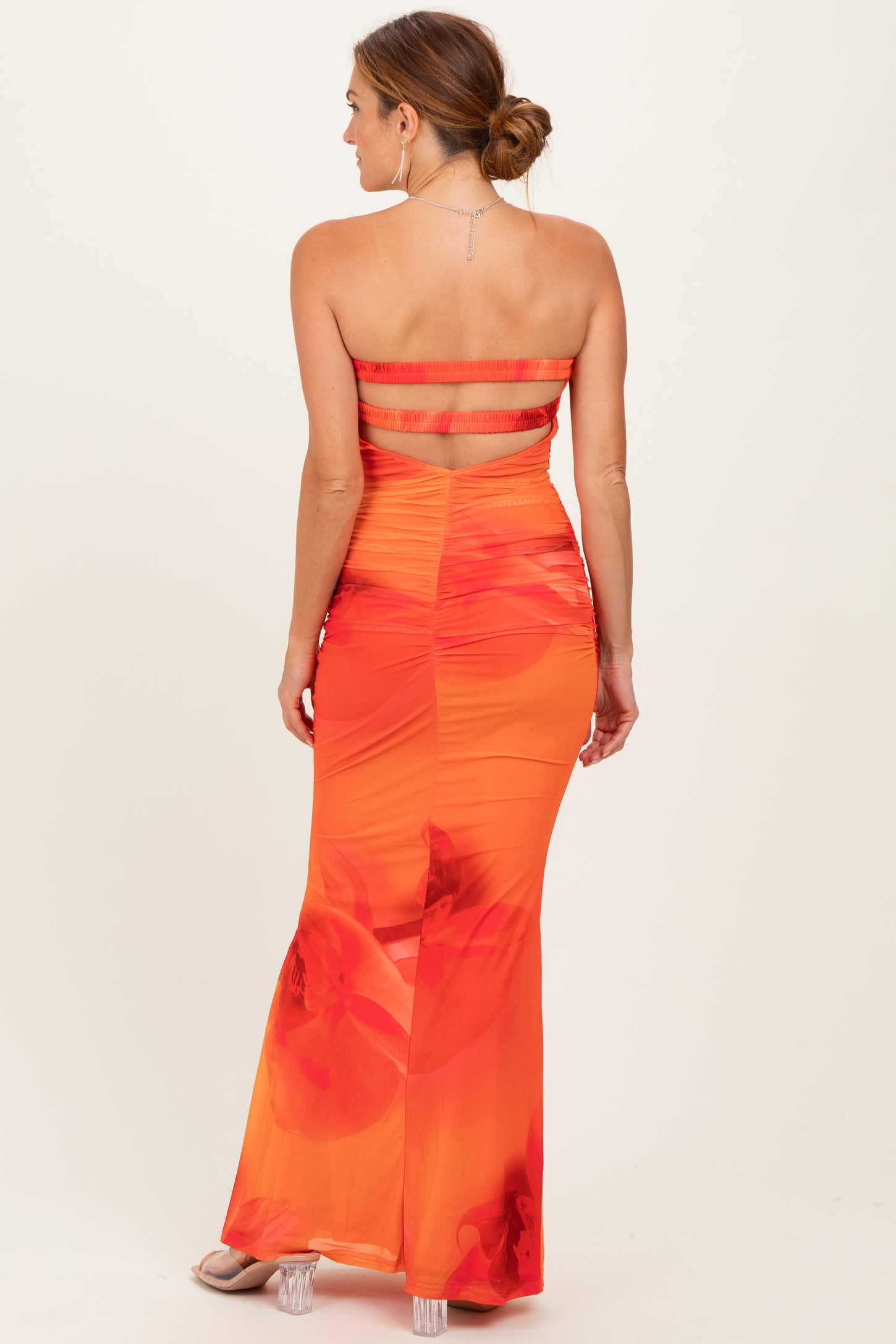 woman wearing a backless red and orange floral maxi dress with a fitted silhouette and cut-out details