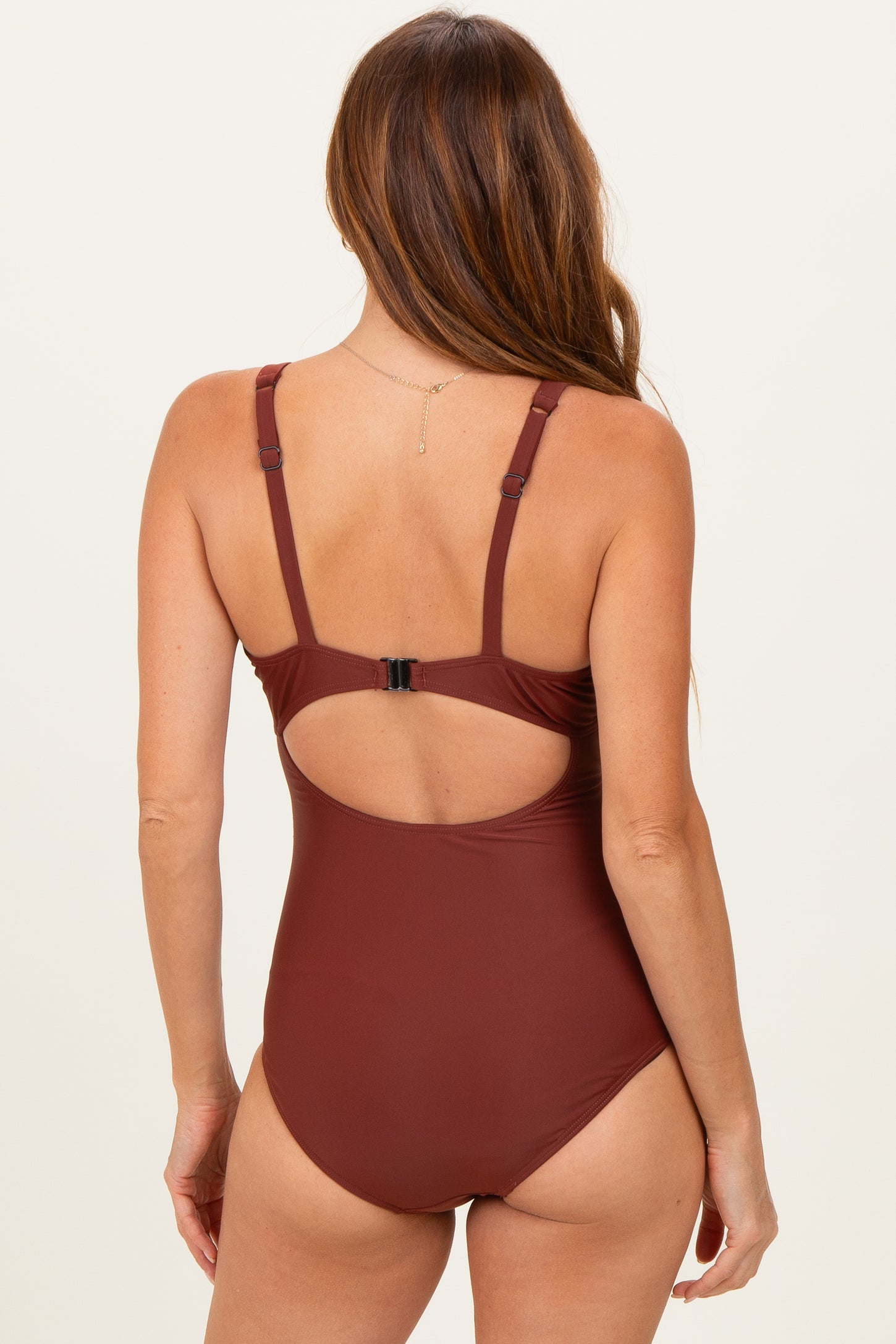 woman wearing a brown one-piece swimsuit with a cutout back detail