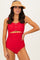 woman wearing a bright red scalloped bikini top with buttons and high-waisted bottom, styled with a straw hat