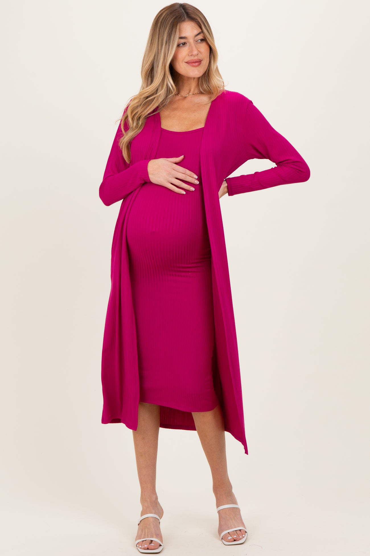 woman wearing a bright pink maternity dress with a matching long cardigan and a visible baby bump
