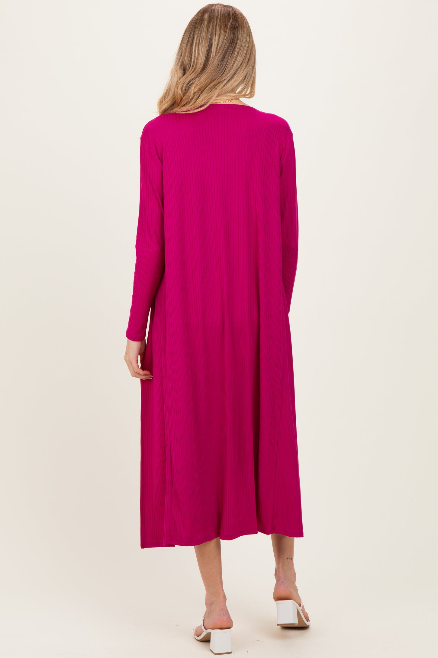 woman wearing a vibrant pink long sleeve maternity dress, showing the back view with a flowy silhouette