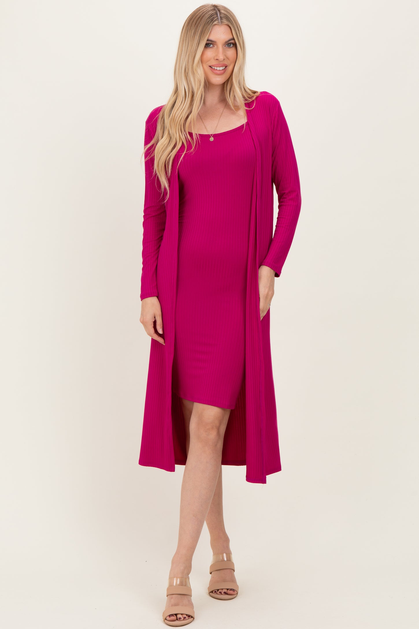 woman wearing a fitted hot pink dress with a matching long cardigan and neutral sandals