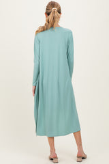 woman wearing a light green maternity duster with long sleeves and a flowy silhouette, viewed from the back