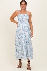 woman wearing a blue floral print maternity dress with adjustable straps and a flowy silhouette, showing her baby bump