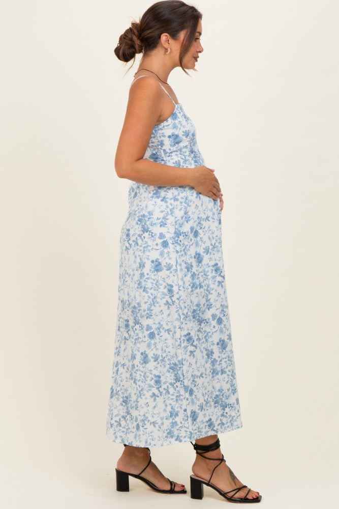 woman wearing a blue and white floral maternity dress, showing her baby bump from the side
