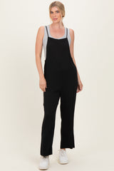 woman wearing a black sleeveless jumpsuit over a gray tank top with white sneakers