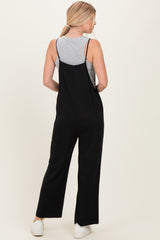 woman wearing a black jumpsuit over a gray tank top, viewed from the back, with straight leg fit and spaghetti straps