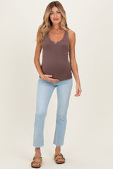 woman wearing a brown ribbed maternity tank top and light blue cropped jeans, showing her baby bump