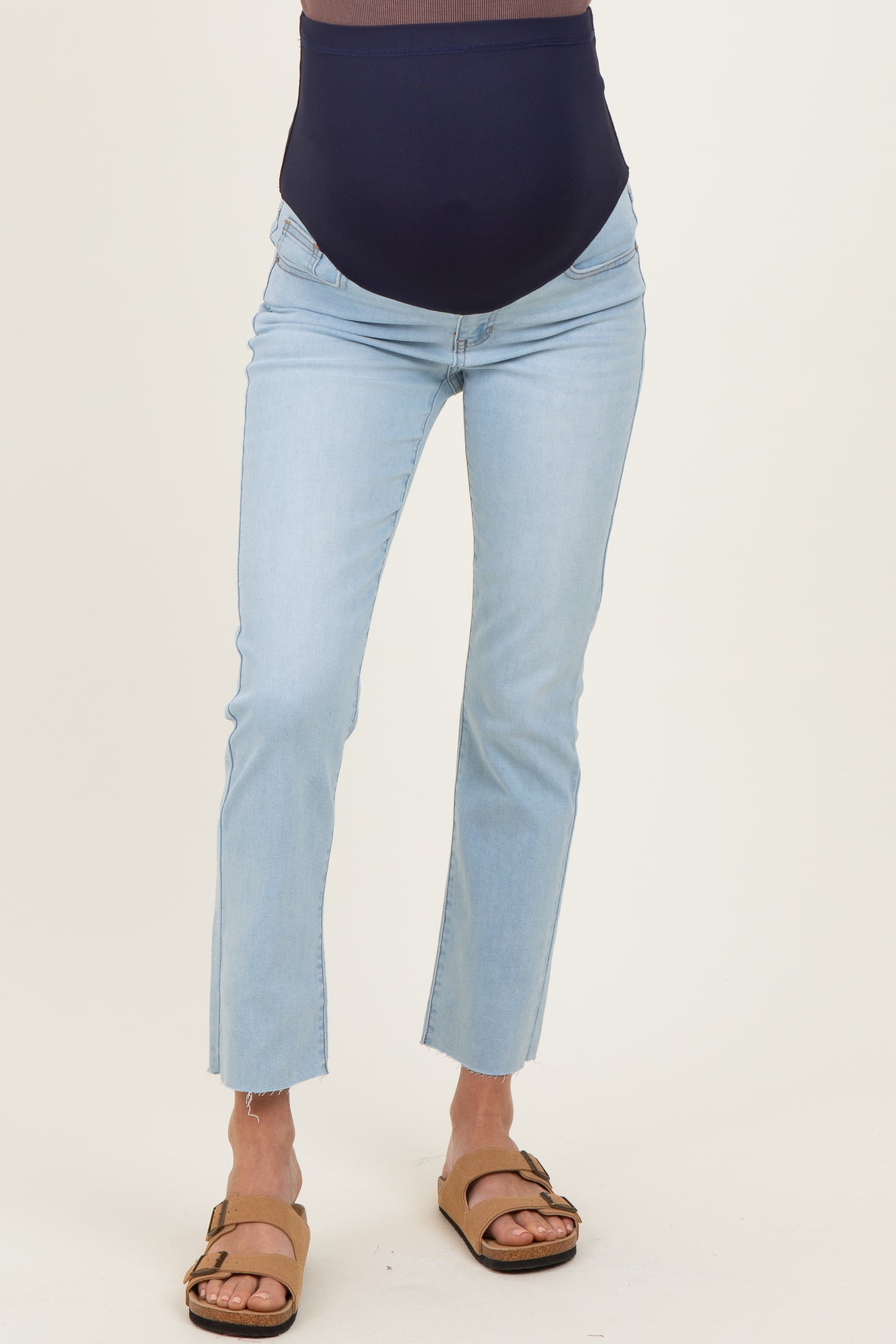 woman wearing light wash maternity jeans with a dark navy over-the-bump band and frayed hem