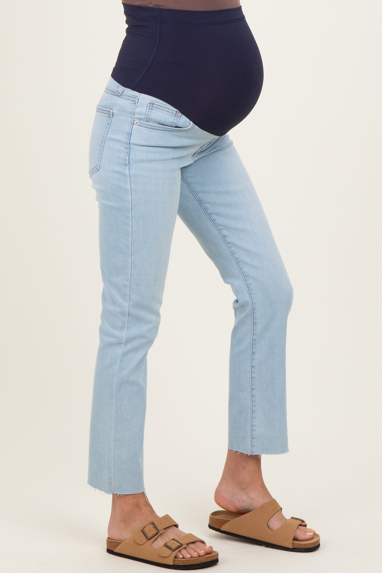 woman wearing light blue maternity jeans with a dark blue over-the-bump panel and a baby bump visible