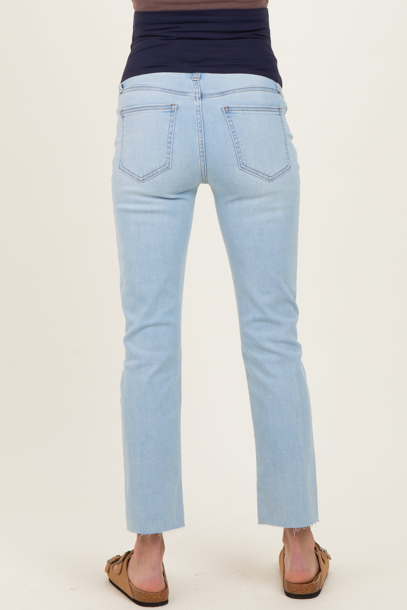 woman wearing light blue maternity jeans with a fitted waistband and cropped hem, showing the back view