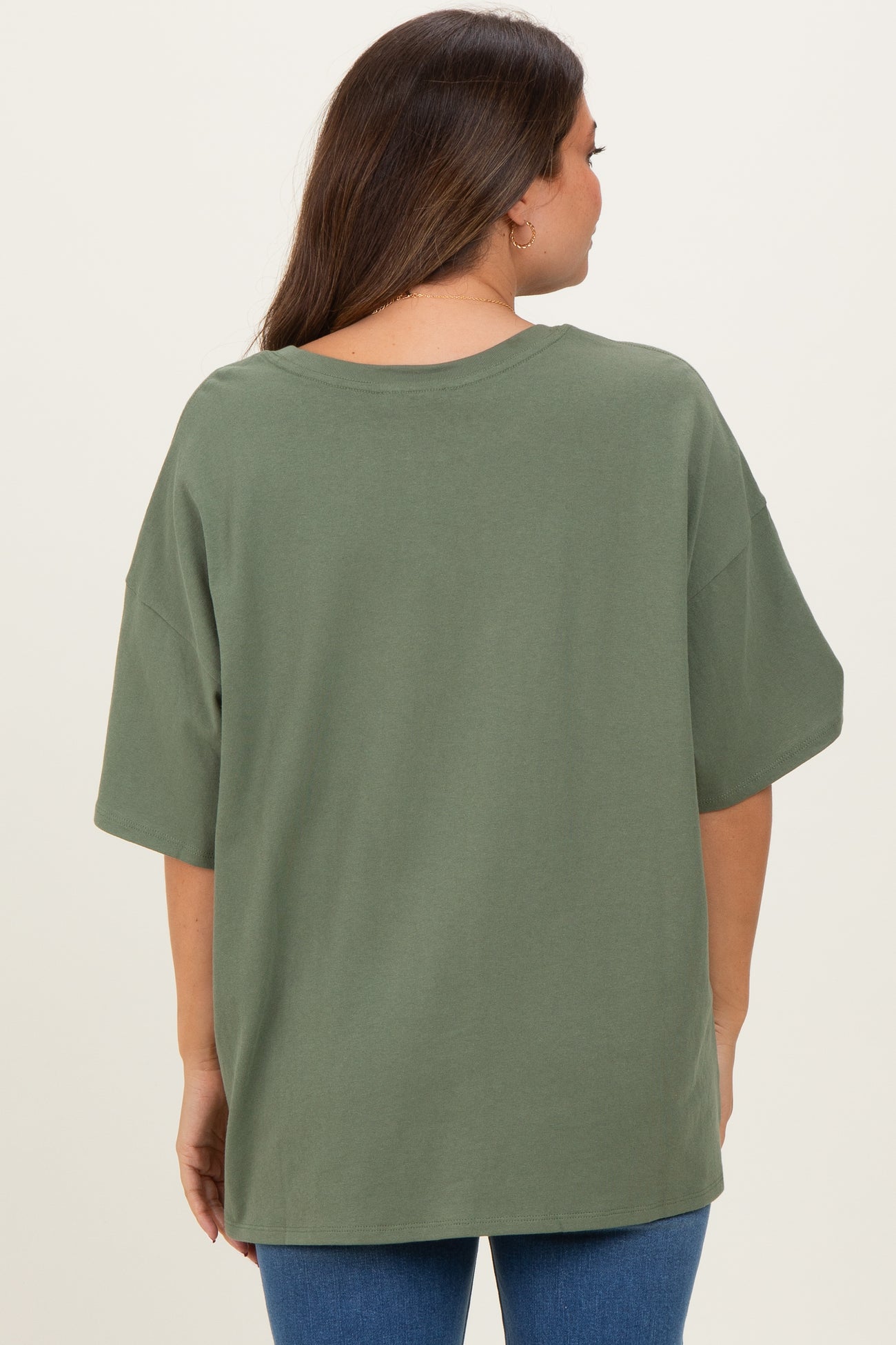 woman wearing an olive green oversized maternity t-shirt from the back, paired with blue jeans