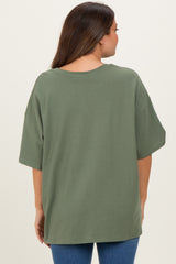 woman wearing an olive green oversized maternity t-shirt from the back, paired with blue jeans