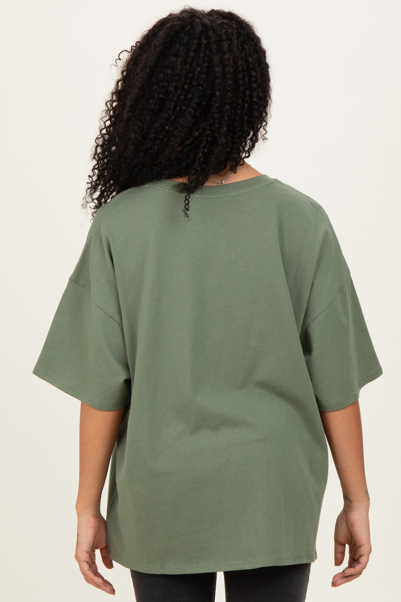 woman wearing an oversized olive green t-shirt with short sleeves, viewed from the back