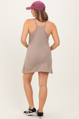 woman wearing a beige maternity slip dress, showing the back view, paired with a purple cap and black sneakers