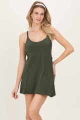woman wearing a dark green sleeveless dress with two front pockets and a relaxed fit