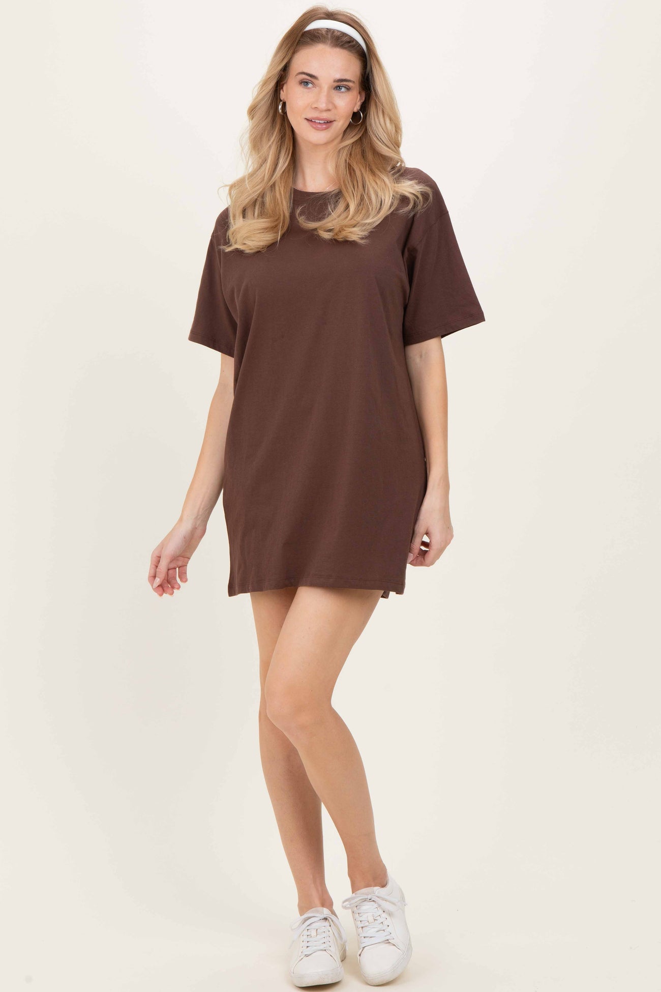 woman wearing a brown oversized t-shirt dress with short sleeves and a relaxed fit, paired with white sneakers