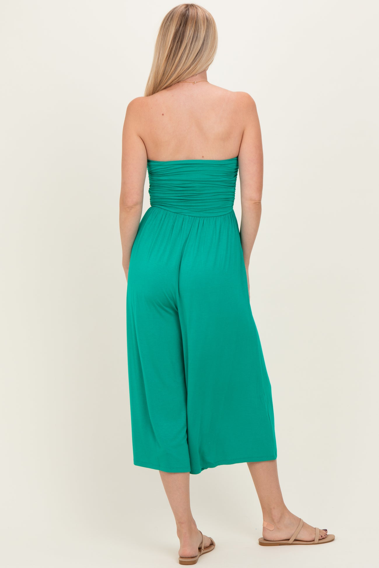 woman wearing a green strapless jumpsuit with a gathered back and wide legs