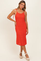 woman wearing a bright red knitted midi dress with tie straps and ribbed texture, posing elegantly