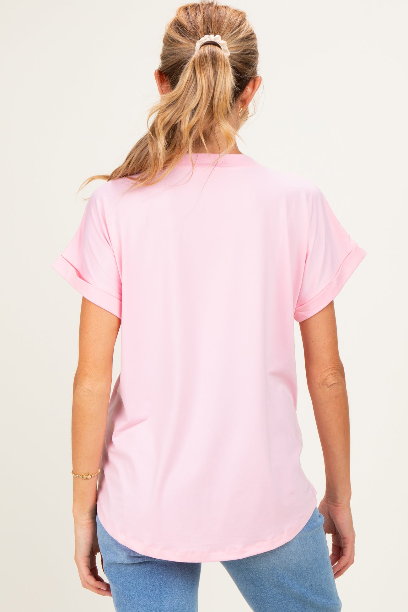 woman wearing a light pink maternity top with short sleeves, shown from the back