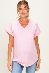 woman wearing a light pink v-neck maternity top with rolled sleeves and a pocket, showing her baby bump