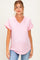 woman wearing a light pink v-neck maternity top with rolled sleeves and a pocket, showing her baby bump