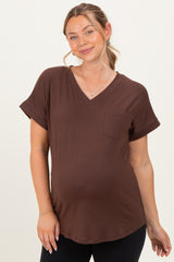 woman wearing a brown v-neck maternity top with rolled sleeves and a front pocket, showing a baby bump