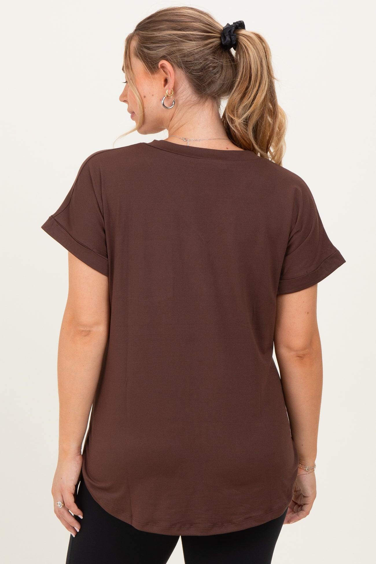 woman wearing a brown short sleeve maternity top, viewed from the back, with relaxed fit and rolled sleeves