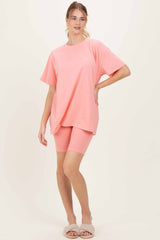 woman wearing a pink oversized t-shirt and matching biker shorts, styled with cozy slippers