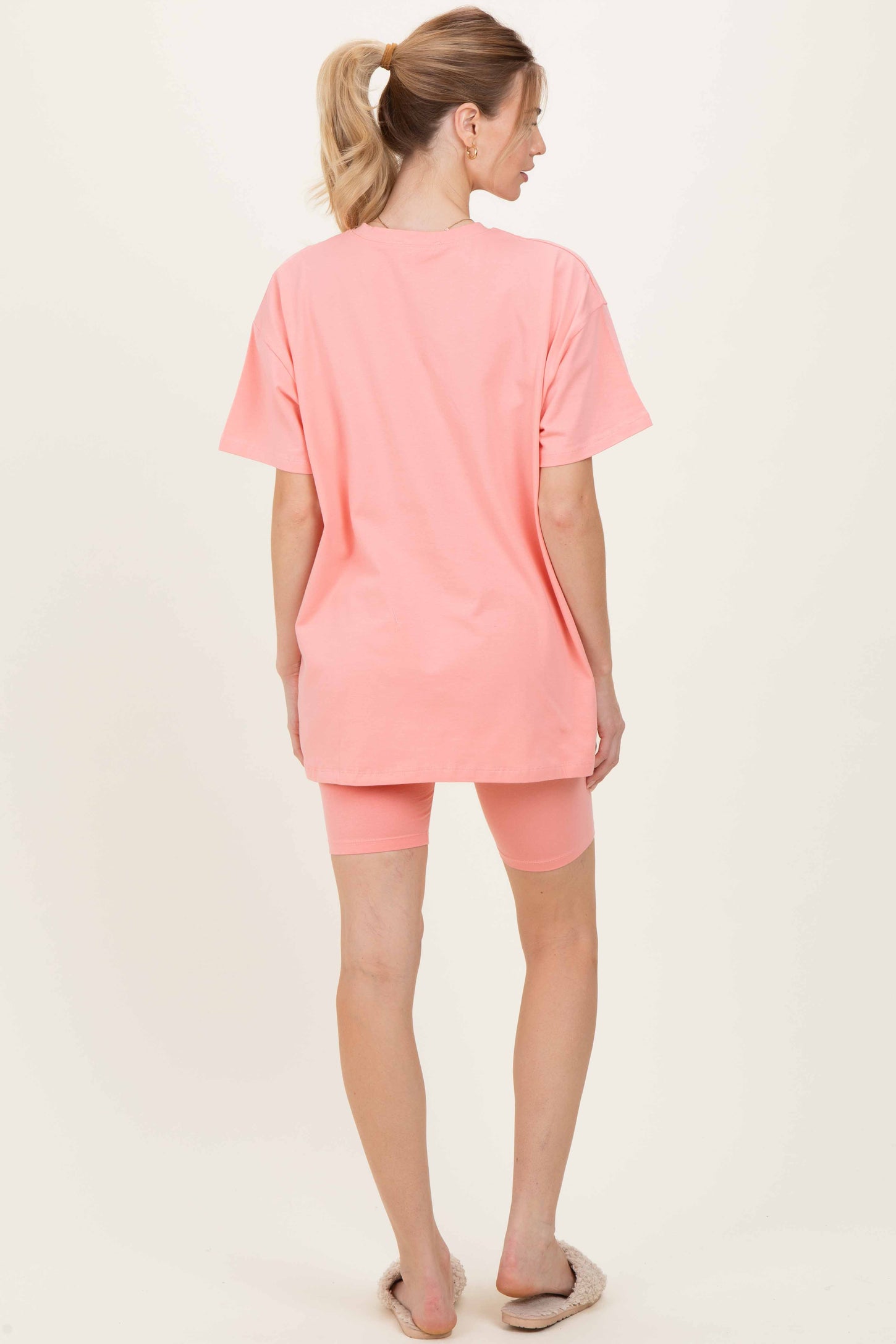 woman wearing a pink oversized t-shirt and matching bike shorts, showing the back view