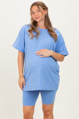 woman wearing a light blue oversized maternity t-shirt and matching biker shorts, holding her baby bump