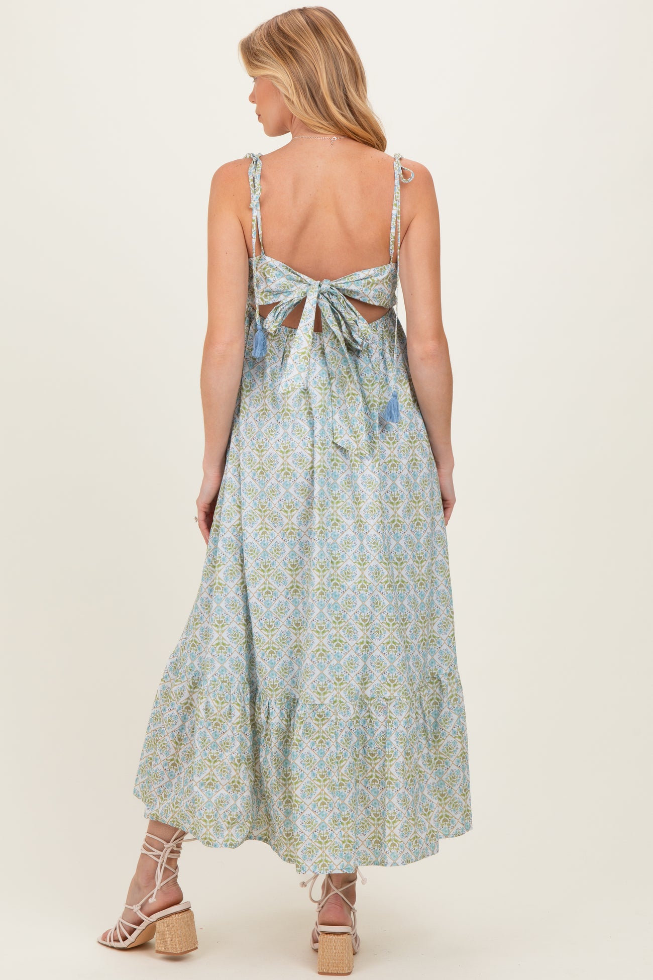 woman wearing a floral patterned maternity maxi dress with a tie-back and tassel details