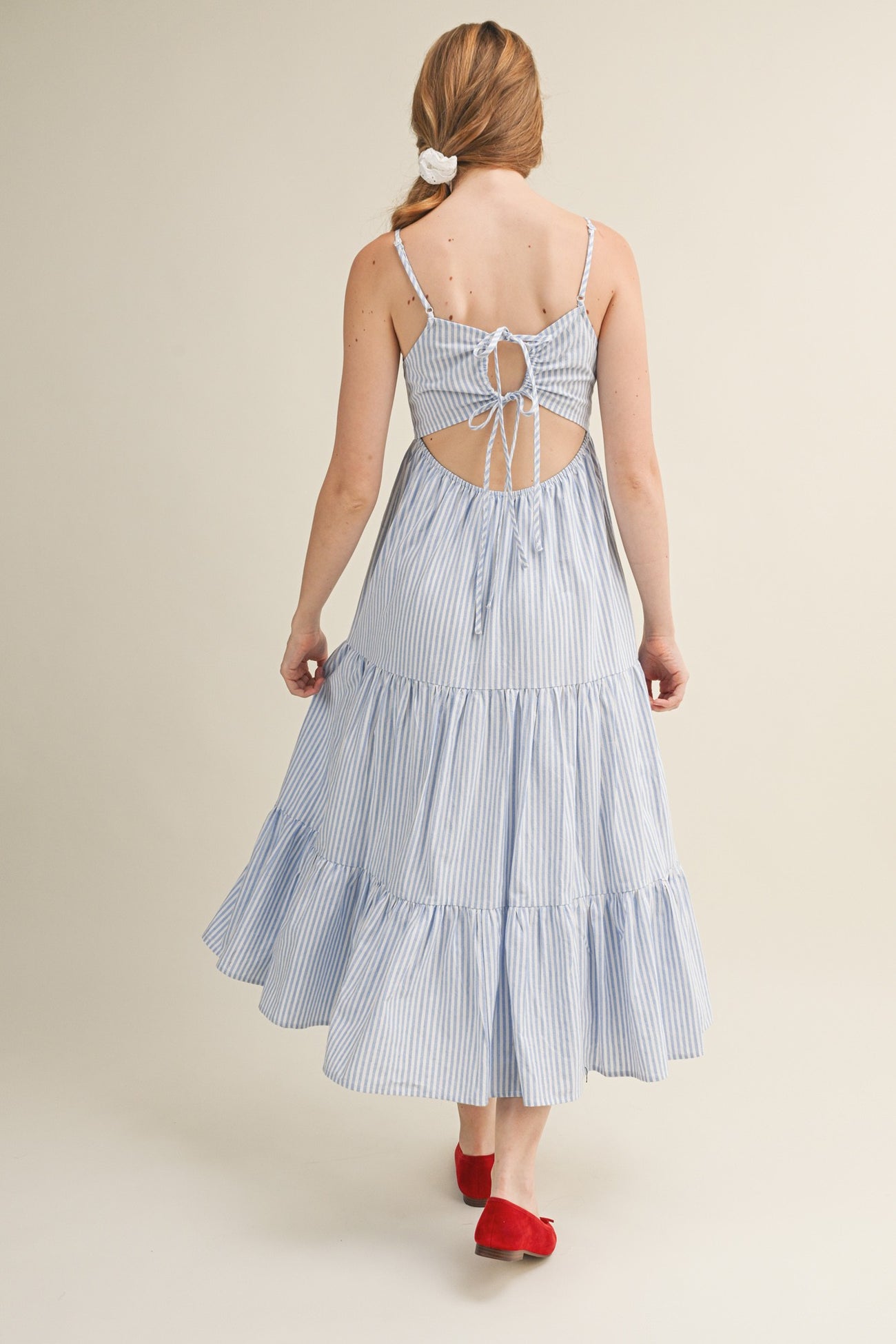 woman wearing a blue and white striped maxi dress with a back tie detail and tiered skirt, shown from the back