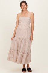 woman wearing a striped light pink maternity maxi dress with adjustable straps and a tiered skirt, smiling at the camera