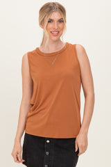 woman wearing a rust sleeveless top with a braided neckline and a black denim skirt