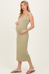 woman wearing a light olive green midi maternity dress, holding her baby bump