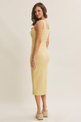 woman wearing a yellow floral midi dress with a fitted silhouette and back view, paired with beige wedge sandals